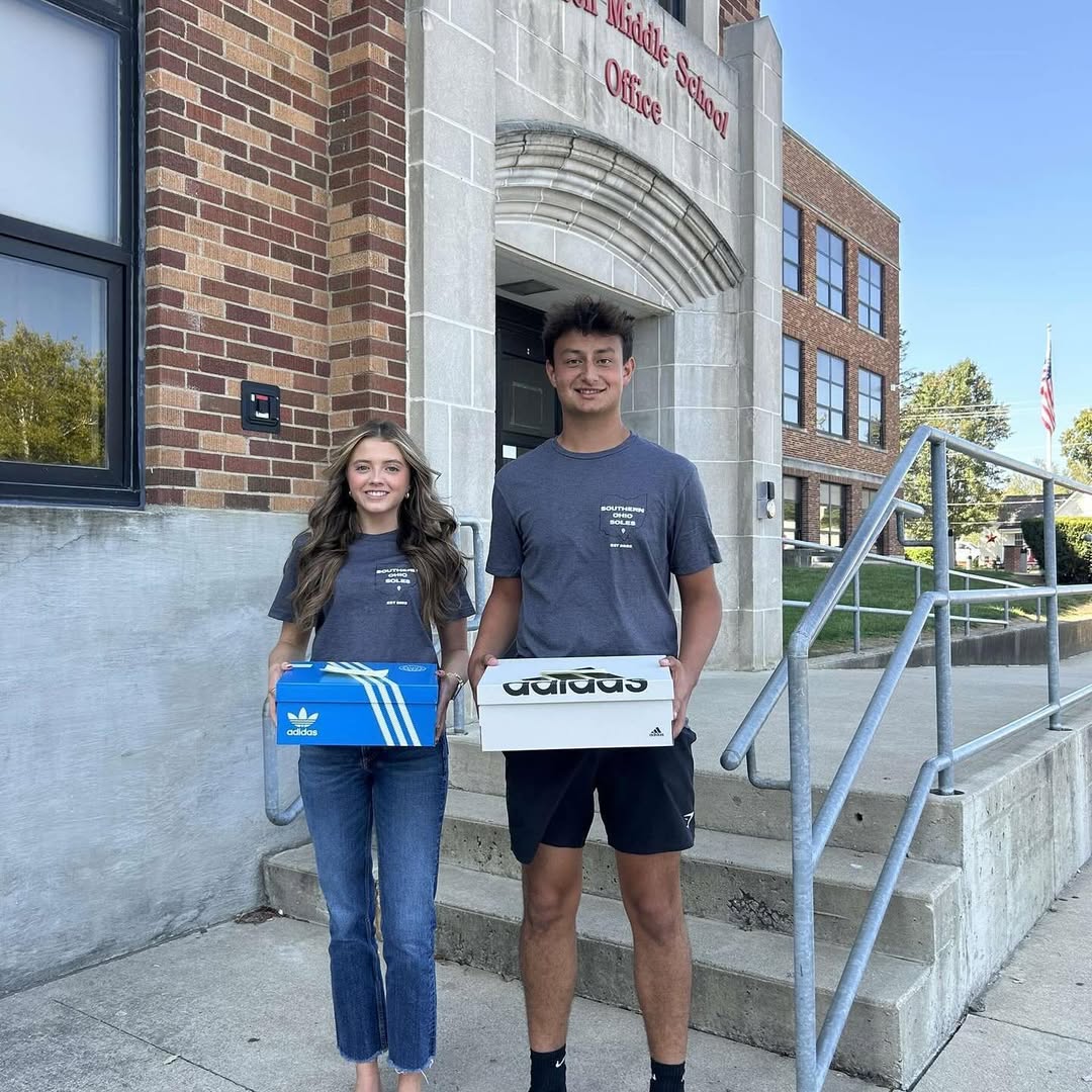 Southern Ohio Soles student representatives holding new shoes outside a school